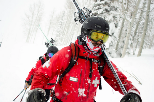 Image of Ski Patrol workers carrying skis and walking through snow